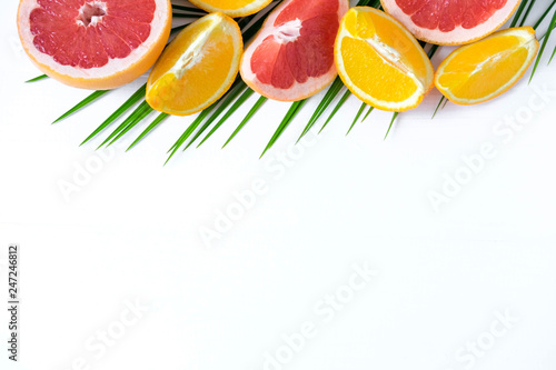 Fototapeta Naklejka Na Ścianę i Meble -  The basis for the banner with palm leaf and fruit. Grepfruit, orange, palm leaf with space for copispeysa. Frame for text with leaf of palm tree and fruit on a wooden background