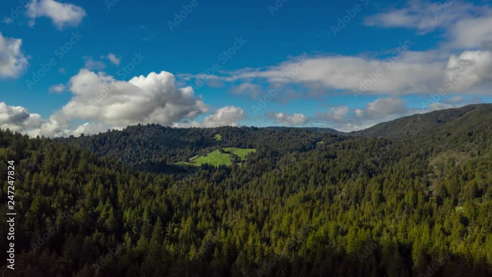 Aerial hyper-lapse flyping over a Redwood forest in California. Timelapse, clouds moving fast while flying towards the landscape. Beautiful clear view, billowy white clouds. Aerial hyper-lapse flyping over a Redwood forest in California. Timelapse, clouds moving fast while flying towards the landscape. Beautiful clear view, billowy white clouds.