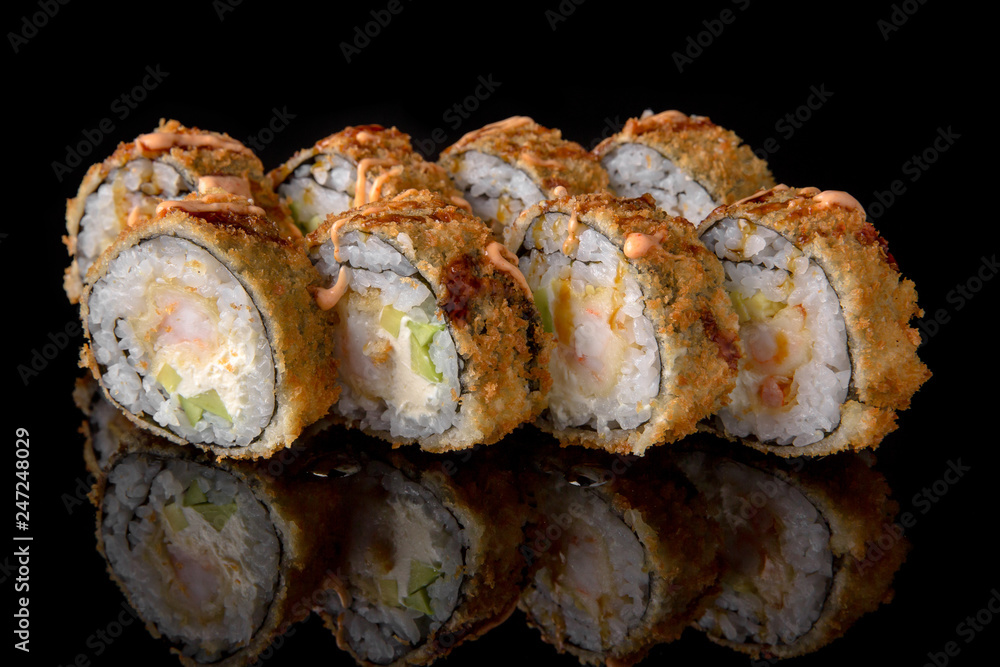 Hot fried Sushi Roll with shrimp, scallop, avocado and cheese on black background. Sushi menu. Japanese food. Hot fried Sushi Roll with shrimp, scallop, avocado and cheese on black background. Sushi menu. Japanese food.