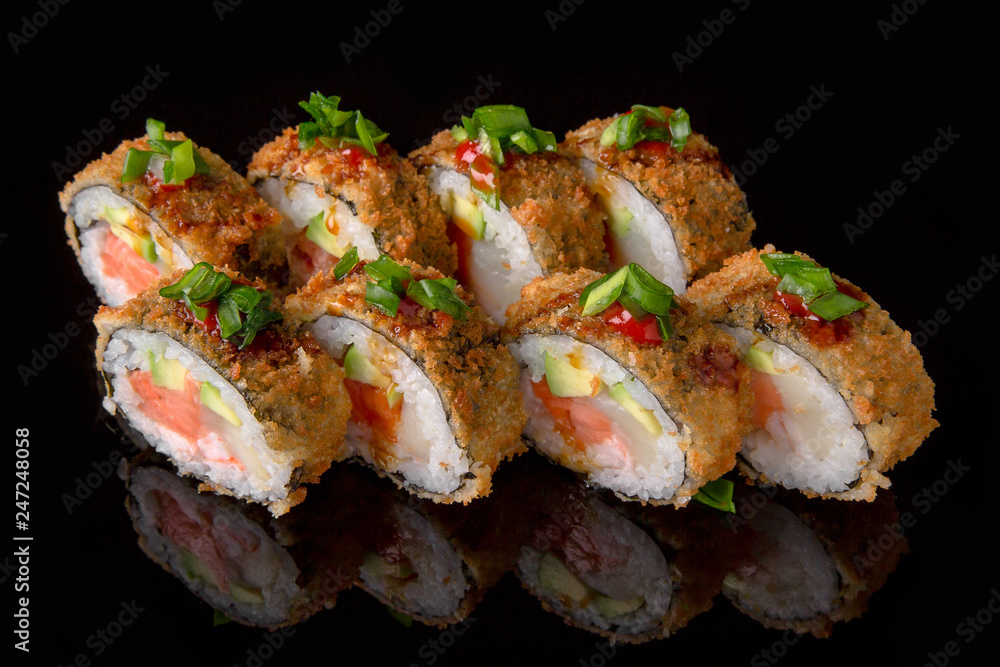 Hot fried Sushi Roll with smoked salmon, scallops, shrimp, avocado and cheese on black background. Sushi menu. Japanese food. Hot fried Sushi Roll with smoked salmon, scallops, shrimp, avocado and cheese on black background. Sushi menu. Japanese food.