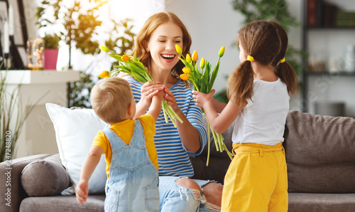 Happy mother's day! Children congratulates moms and gives her a gift and flowers