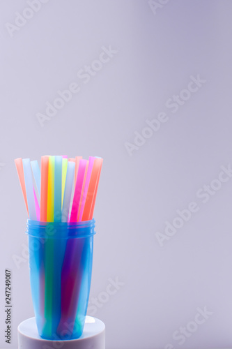Bright multi-colored plastic tubules in a translucent blue glass on a white background