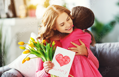 happy mother's day! child daughter   gives mother a bouquet of flowers to tulips and postcard.