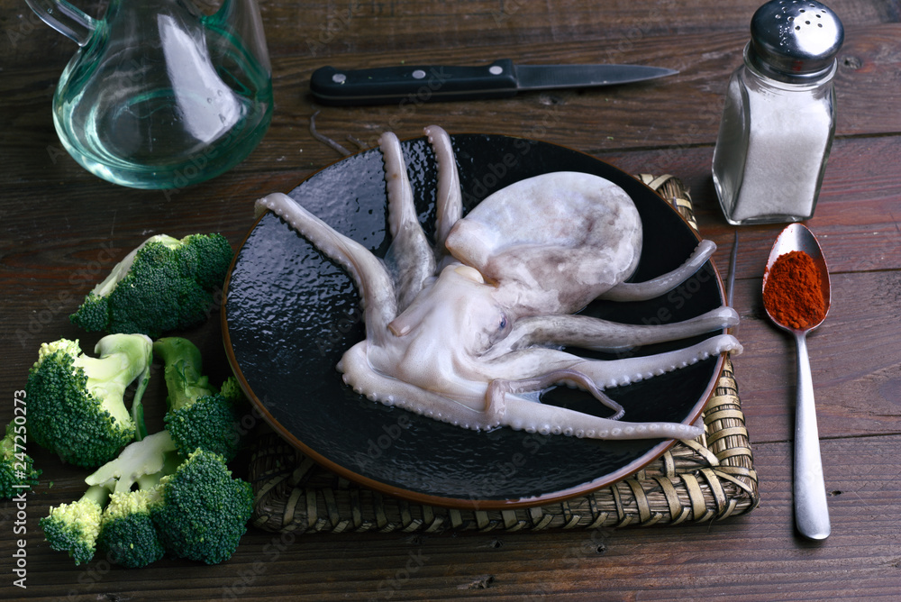 raw octopus in porcelain dish on rustic wood