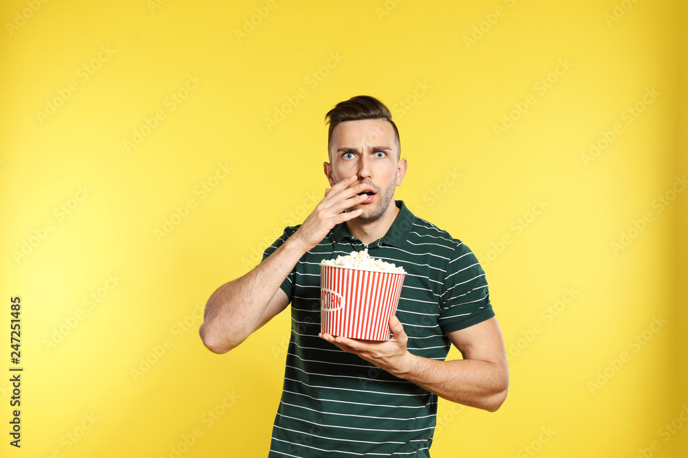 Obraz premium Emotional man with popcorn during cinema show on color background