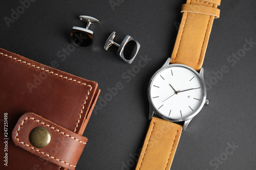 Stylish wrist watch, cuff links and wallet on black background. Fashion accessory