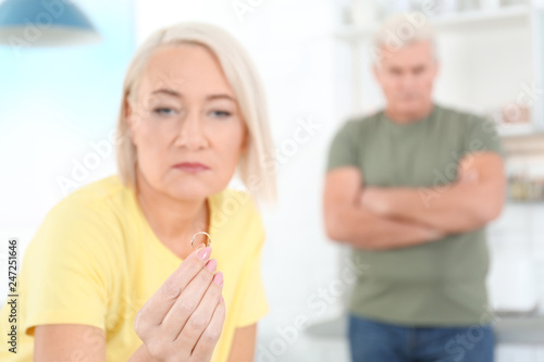 Mature woman looking on wedding ring after conflict with her husband at home. Relationship problems