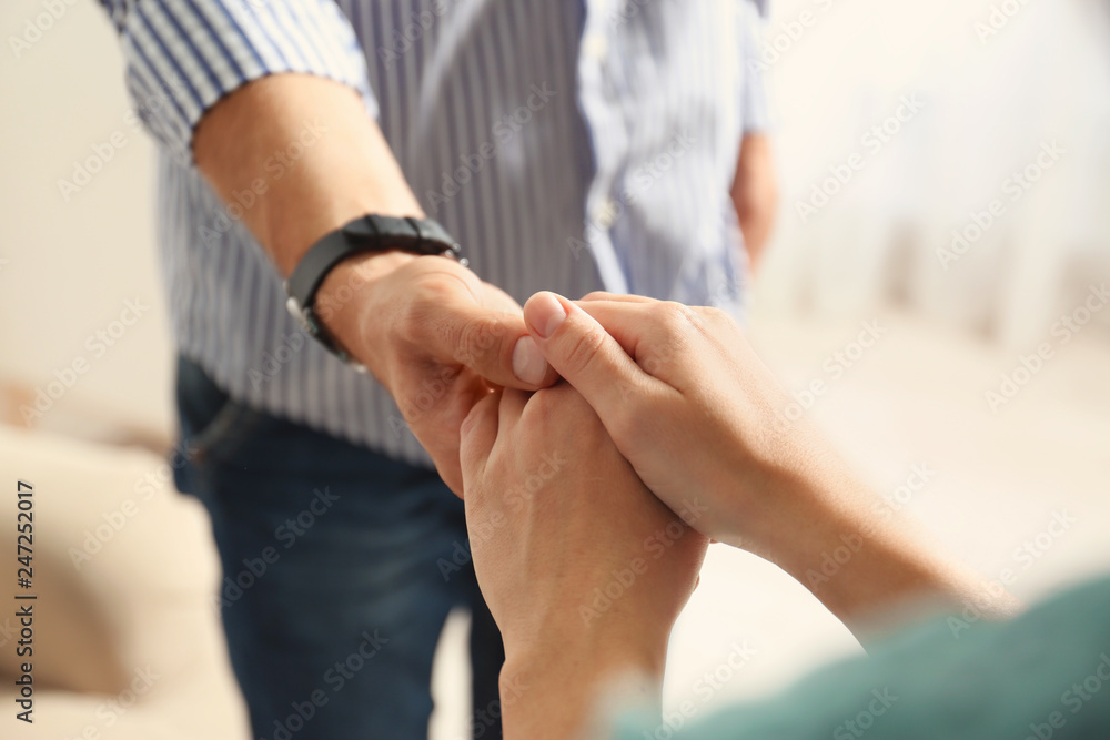 Fototapeta premium Man and woman holding hands on light background, closeup. Help and support concept