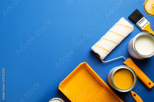 Flat lay composition with paint cans, decorator tools and space for text on color background photo