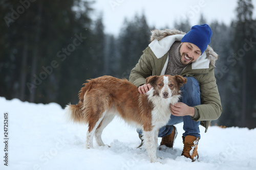 Man with cute dog near forest. Winter vacation