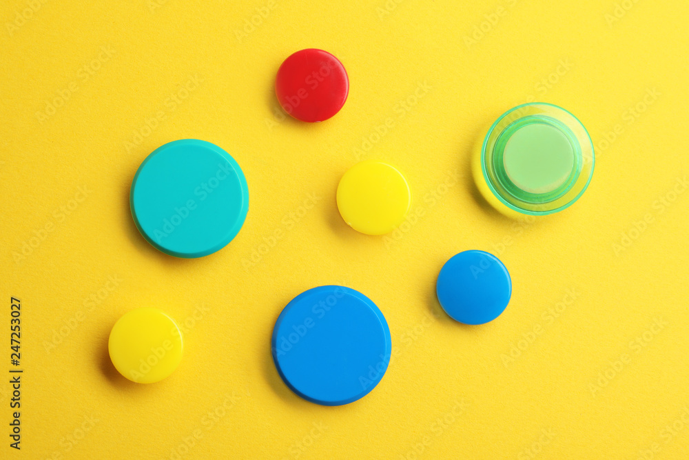 Bright magnets on color background, top view