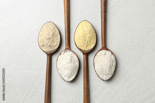 Spoons with different types of flour on table, top view