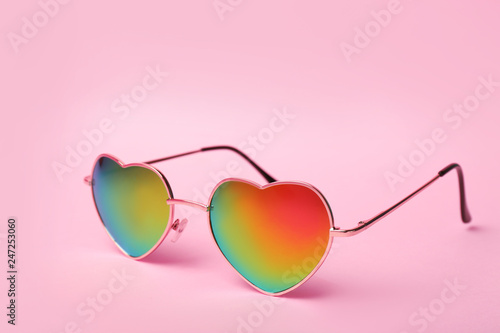 Modern heart shaped glasses on color background