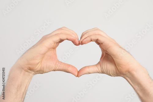 Man making heart with his hands on light background  closeup