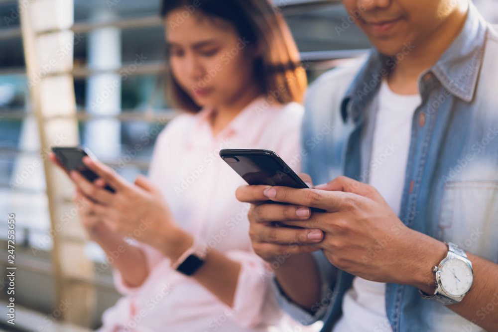 Young people are using smartphone and smiling while sitting on free time. technology concept Young people are using smartphone and smiling while sitting on free time. technology concept