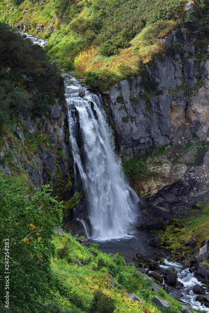 Cascade of mountain waterfall, high-mountain vegetation - green trees and bushes Cascade of mountain waterfall, high-mountain vegetation - green trees and bushes