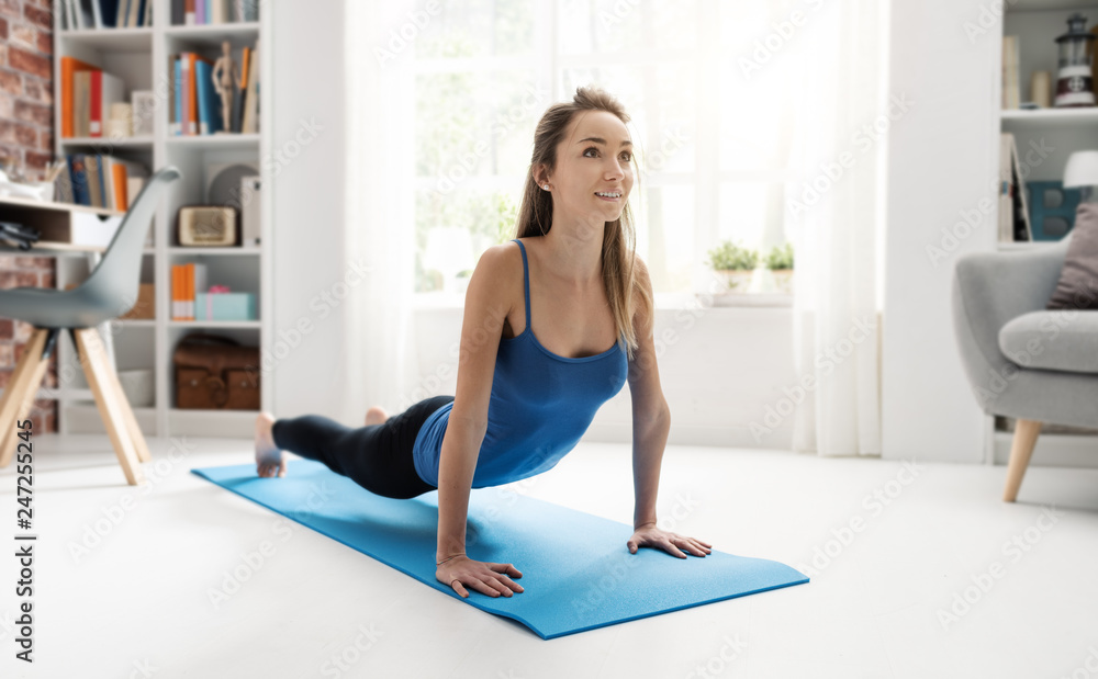 Obraz premium Young woman exercising in her living room at home