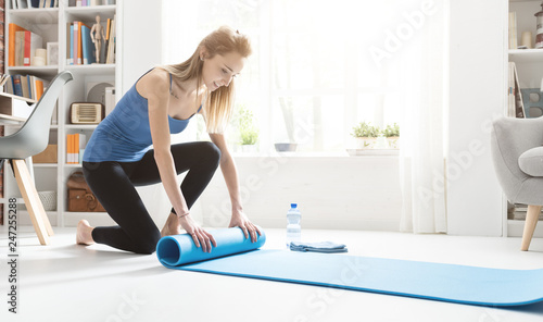 Young woman rolling her yoga mat after exercising