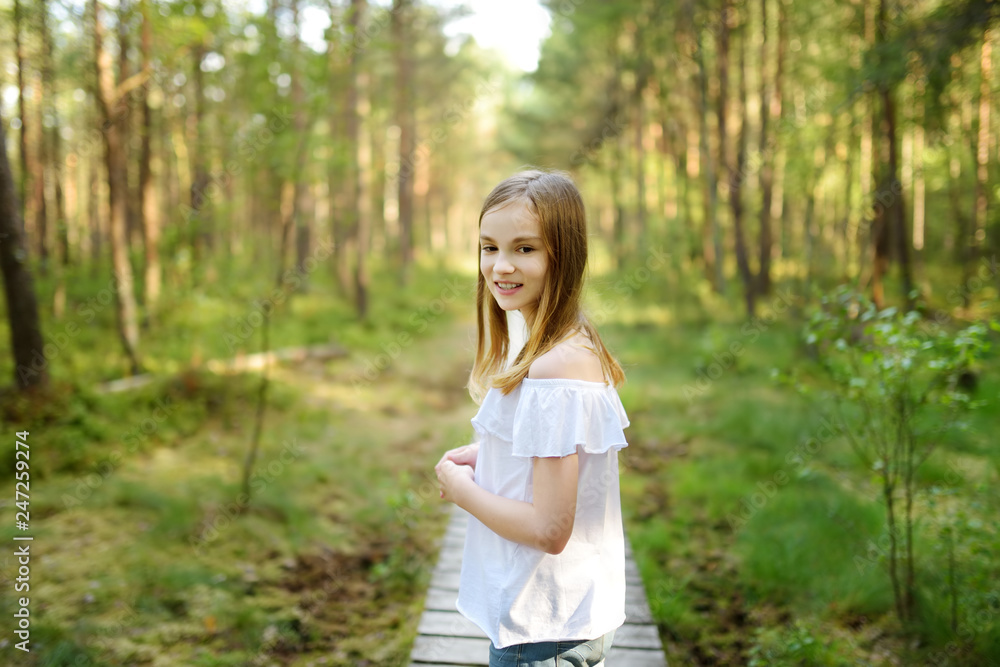 Cute young girl having fun during forest hike on beautiful summer day. Active family leisure. Cute young girl having fun during forest hike on beautiful summer day. Active family leisure.