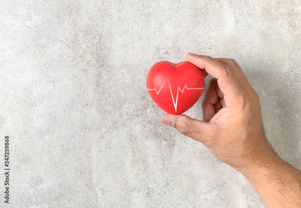 Man holding a red heart shape on marble table Man holding a red heart shape on marble table