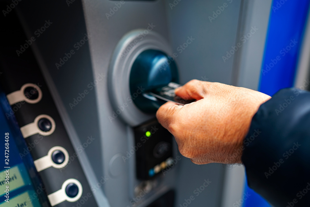 Fototapeta premium man pushing credit card at cash dispenser