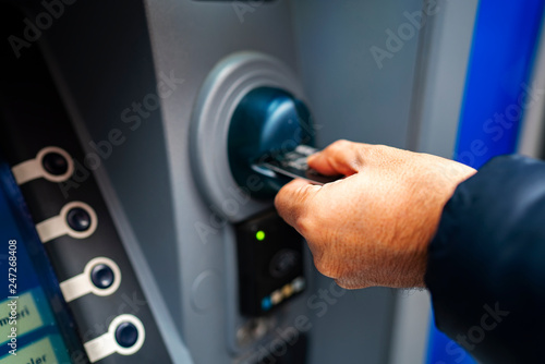 man pushing credit card at cash dispenser