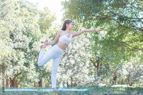 Young woman exercising and doing yoga in the garden with sunlight ,healthy concept