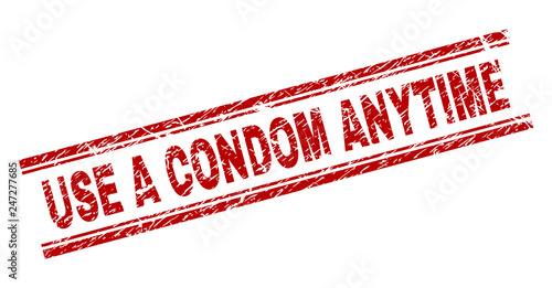 USE A CONDOM ANYTIME seal print with corroded texture. Red vector rubber print of USE A CONDOM ANYTIME tag with dust texture. Text tag is placed between double parallel lines.