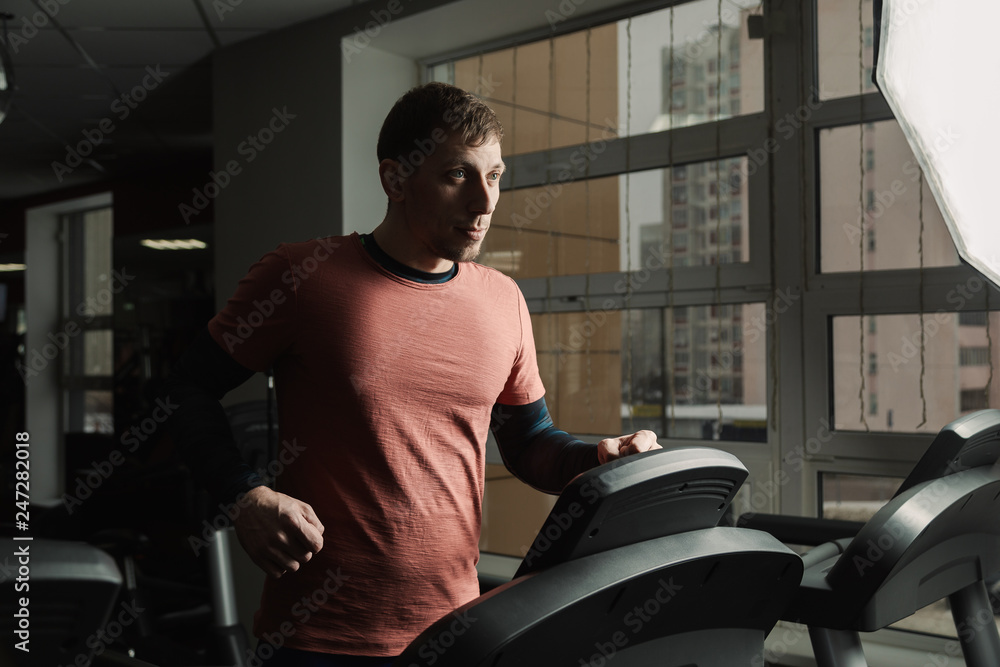 Handsome athletic man exercising on the treadmill in the gym. Handsome athletic man exercising on the treadmill in the gym.