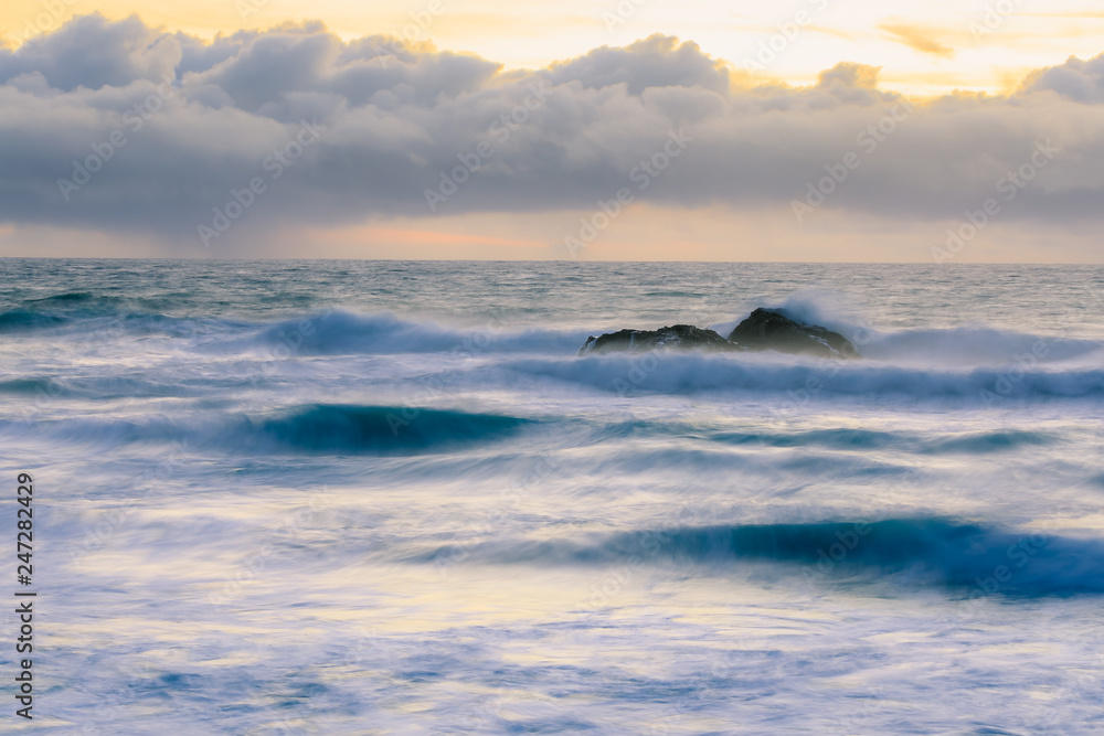 Fototapeta premium Pastel colors of sunset and silky water from long exposure of waves crashing by Pigeon Point Lighthouse on Northern California Pacific Ocean coastline at sunset