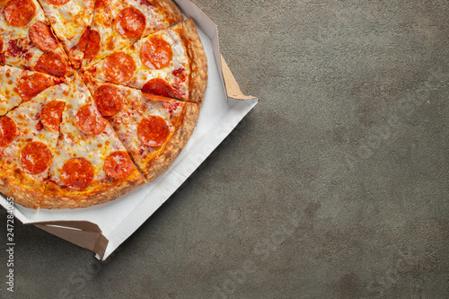 Tasty pepperoni pizza in a box on brown concrete background. Top view of hot pepperoni pizza. With copy space for text. Flat lay photo