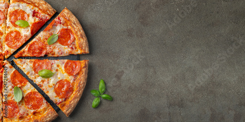 Tasty pepperoni pizza with basil on brown concrete background. Top view of hot pepperoni pizza. With copy space for text. Flat lay