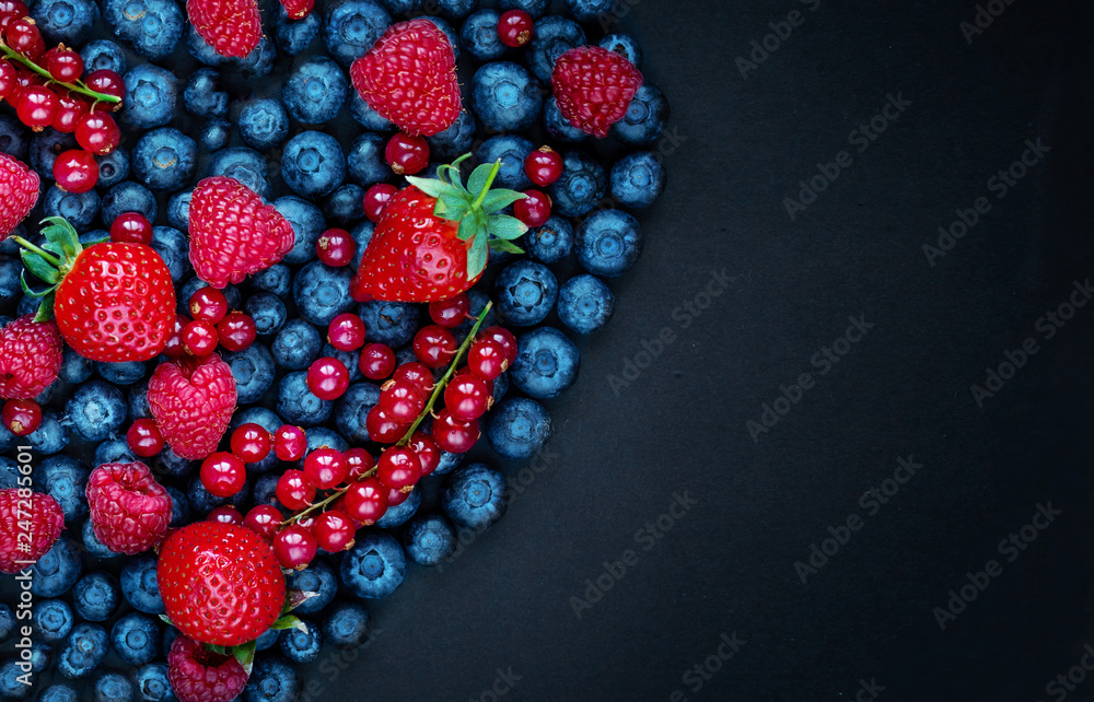 Berry mix on a black background with copy space. Strawberry, Raspberry, Red currant, Blueberry and Blackberry, top view Berry mix on a black background with copy space. Strawberry, Raspberry, Red currant, Blueberry and Blackberry, top view