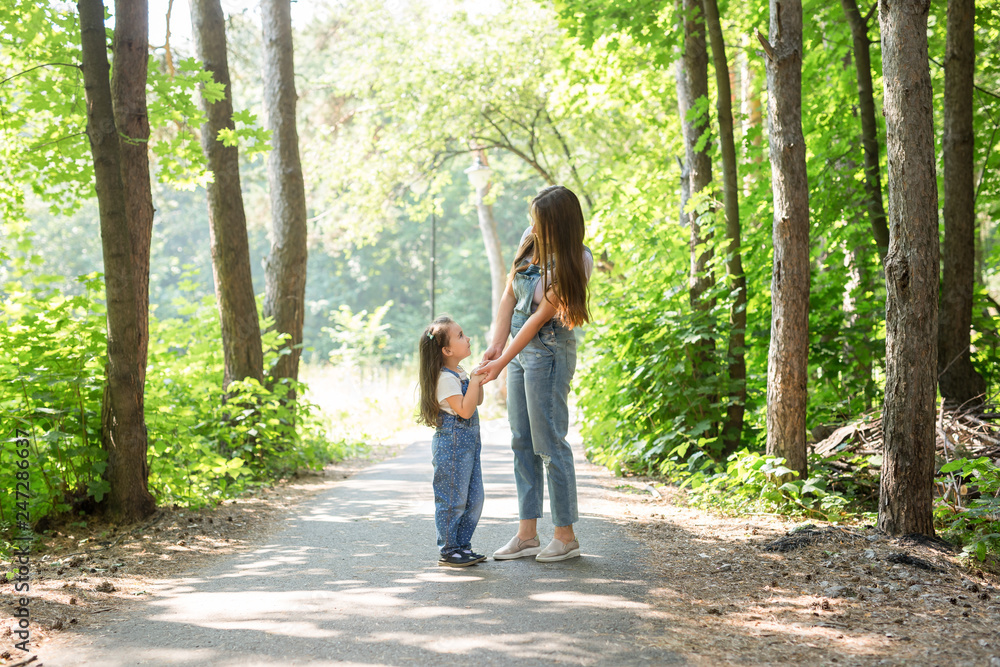 Family and nature concept - Mother with daughter walking in the green park Family and nature concept - Mother with daughter walking in the green park
