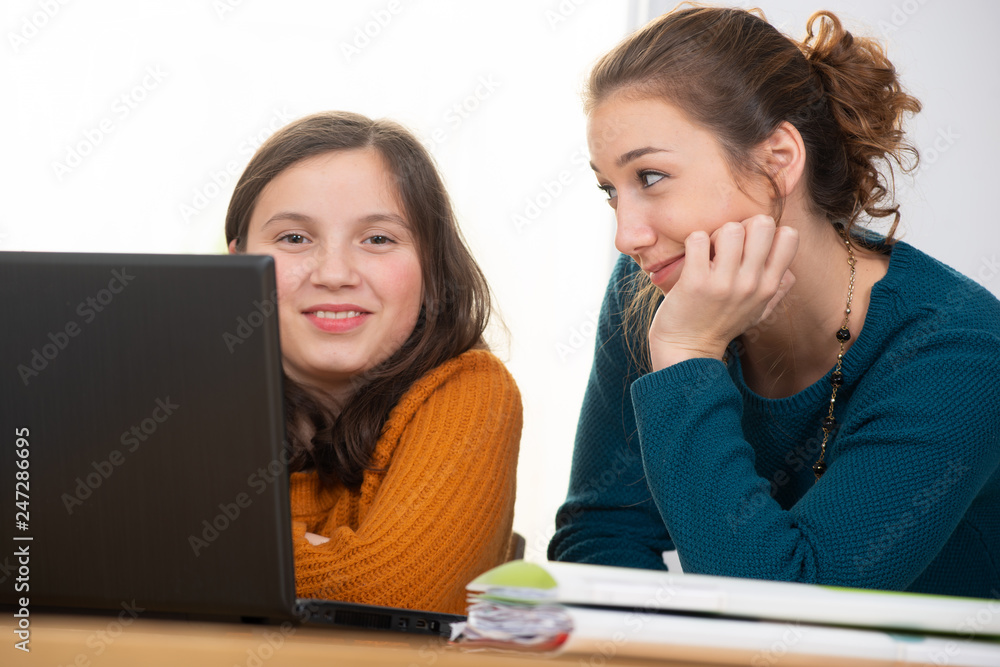 young woman helps a teen girl with homework young woman helps a teen girl with homework