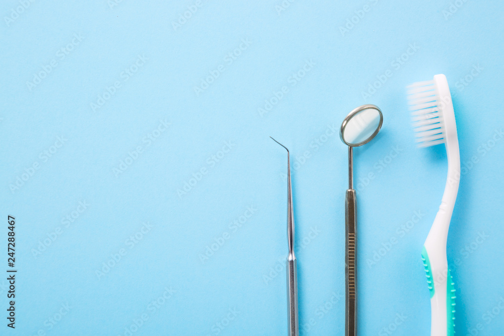 Dental health and teethcare concept. Dentist tools. Professional steel dental instrument with a mirror and toothbrush on light blue background with free space.