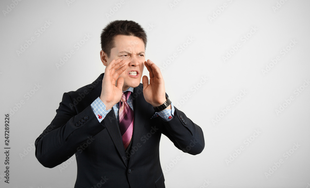 Young businessman in suit on gray background shouting and angry. Scream. Young businessman in suit on gray background shouting and angry. Scream.