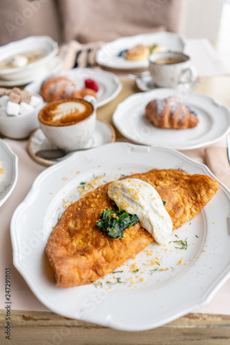 Breakfast. Frittata - italian omelet. Omelette with tomatoes, avocado, spinach and soft cheese. Croissants, coffee and other dishes on the table in the restaurant