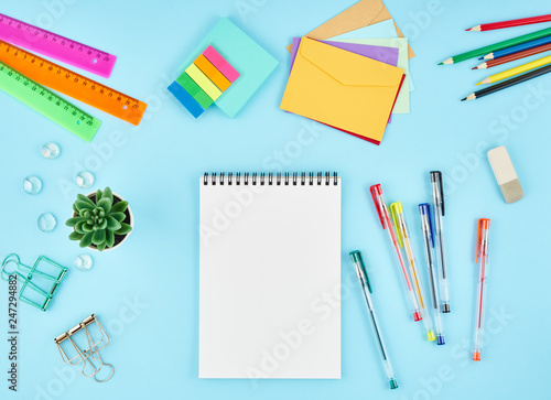 Office supplies, stationery on blue office desktop. Top view of modern bright table with notebook. Mock up, copy space