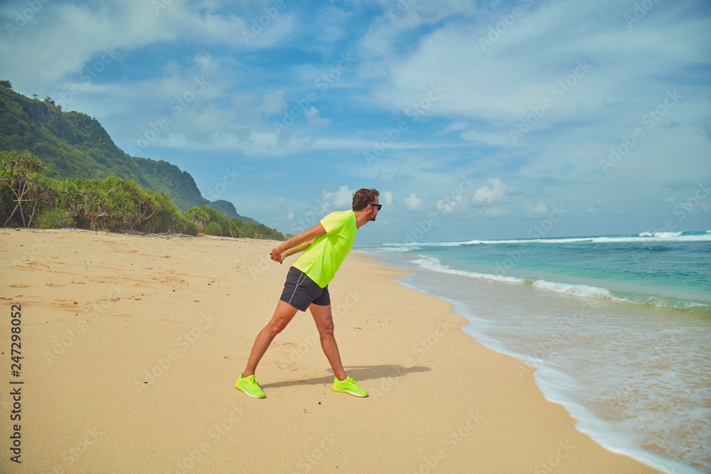 Sportsman stretching on a tropical sandy beach. Sportsman stretching on a tropical sandy beach.