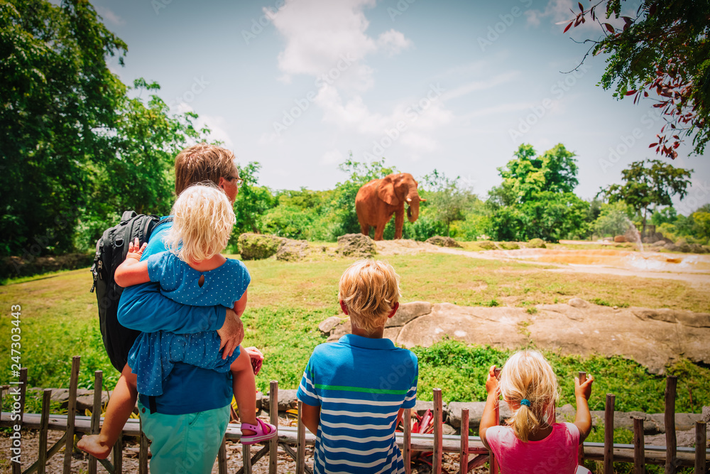 Fototapeta premium ojciec i dzieci patrząc na słonie w zoo