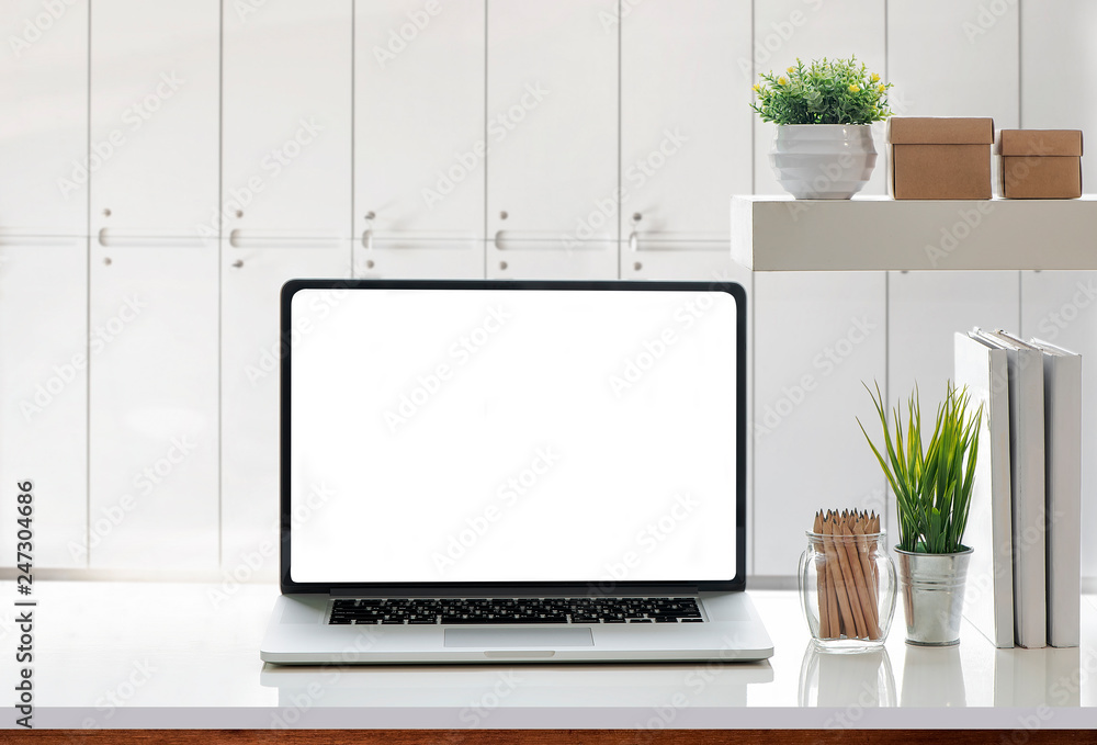 Fototapeta premium Mockup laptop with white screen and supplies on white table.