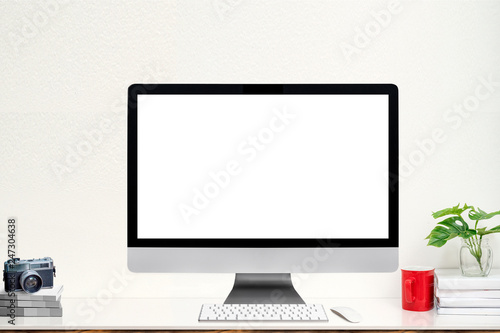 Mockup desktop computer with blank screen and supplies on white table.