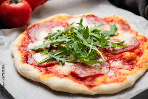 Italian Pizza With Salami And Fresh Arugula. Selective focus. Tasty homemade pizza. Takeout pizza