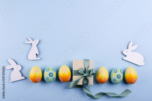 Easter holiday background with eggs. Top view of colorful painted chicken eggs plased  in a row and present box with ribbon photo