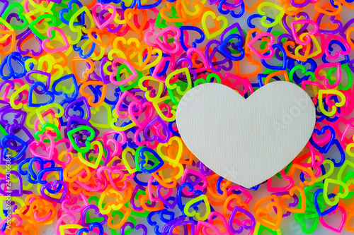 Creamy heart-shaped paper on a colorful heart-shaped plastic on a white background.