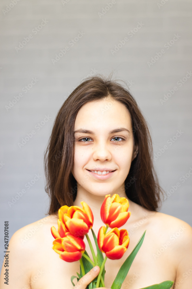 Beautiful girl with flowers tulips in hands on a light background	