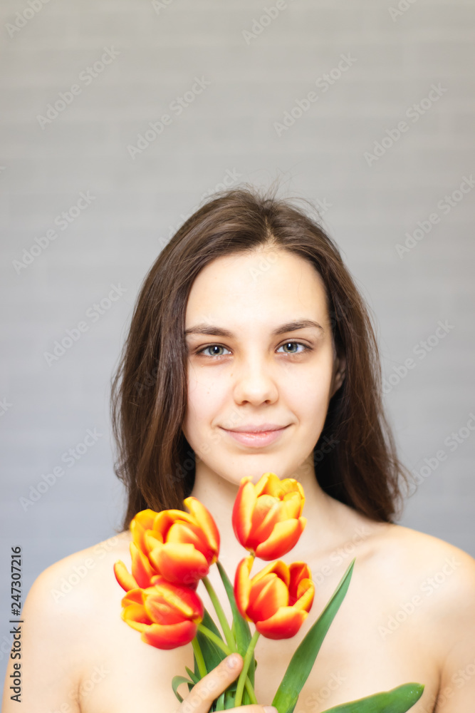 Beautiful girl with flowers tulips in hands on a light background Beautiful girl with flowers tulips in hands on a light background