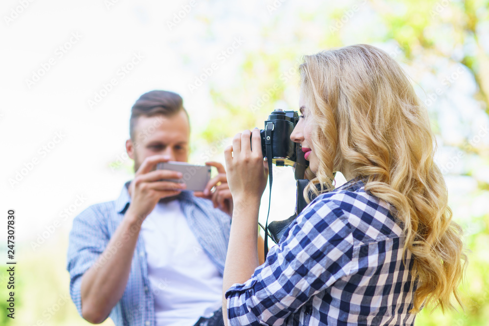 Man and woman taking photos with a camera and a smartphone.