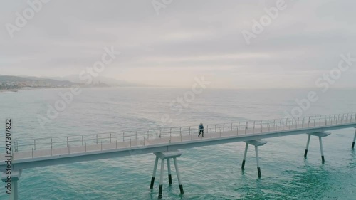 Two senior men in sport outfit walk swiftly on empty boardwalk or pier in early morning light. Healthy lifestyle of active recovery and retirement activities. Comraderie and friendship for elderly photo